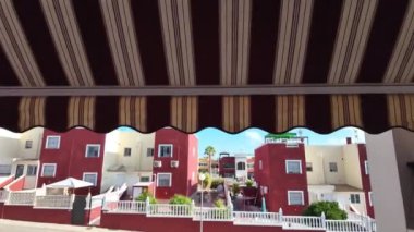 Bir kamera, Dream Hills 'in üstündeki canlı tenteleri, Torrevieja yakınlarındaki 2 kentleşme dairesini, banliyö yaşamından bir parça görüntülemek için yükseliyor..