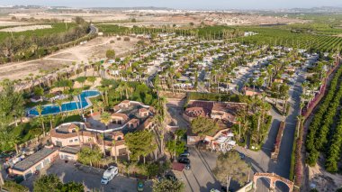 İspanya 'nın Torrevieja kentindeki havuz, palmiye ağaçları ve kırsal kesimde çevreleyen yeşil manzaralı bir tatil beldesi.