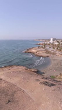 Playa Flamenca ve Cala Mosca plajlarının sakin dikey manzarası İspanya 'nın Orihuela Costa kentinin arka planına karşı eşsiz sahil ve kumlu sahili vurguluyor..
