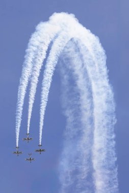 Aerobatik uçaklar, İspanya 'nın San Javier kentindeki bir hava gösterisinde, açık mavi gökyüzüne karşı hassas bir uçuş gerçekleştirerek dramatik bir duman yayını oluşturdular.
