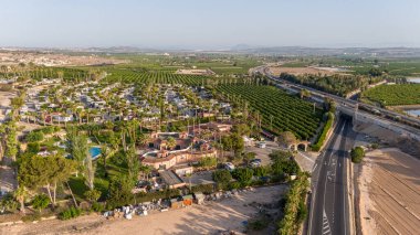 İspanya, Torrevieja yakınlarındaki verimli tarım arazileri ve yollarla çevrili kırsal bir karavan parkının hava manzarası.