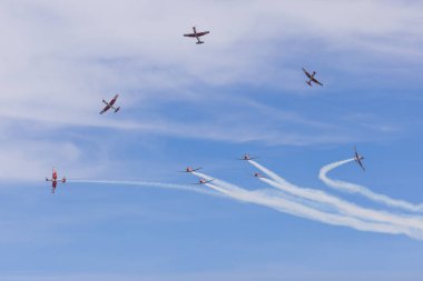 Patrouille Suisse akrobatik uçakları, hava gösterisinde mavi gökyüzünde duman izi bırakarak, karmaşık hava dumanı hareketleri sergiliyorlar.