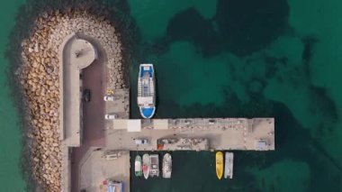 Benidorm 'daki bir marinanın havadan tepeden aşağı görüntüsü, rıhtımdaki kayalıklar ve zümrüt yeşil suların sabit bir insansız hava aracı tarafından yakalandığı temiz bir görüntüsü.