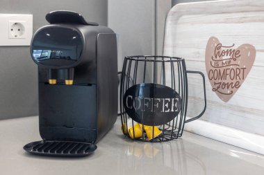Tel kapsül tutacağı ve dekoratif tepsisi olan modern bir kahve makinesi.