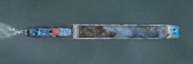 Aerial shot of a cargo barge carrying materials on a river, showcasing industrial transport and shipping operations from above clipart