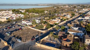 El Chaparral, Torrevieja 'da bir yerleşim bölgesinin havadan görünüşü, evlerin, palmiye çizgili sokakların, park yerlerinin ve arka plandaki tuz gölünün yer aldığı