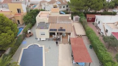 Torrevieja 'da güneş panelleri döşeyen işçilerin sürdürülebilir enerji kullanımını vurguladığı bir villanın havadan görüntüsü.
