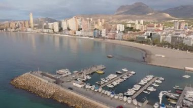 Benidorm 'un sahil manzarası, kumlu sahil ve sakin Akdeniz sularının kıyı şeridi boyunca uzandığı modern gökdelenler ve devam eden inşaatın bir karışımını vurguluyor..