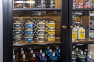 Pomades, mat kremleri ve tımar spreyleri de dahil olmak üzere Layrite saç şekillendirme ürünlerini sergileyen bir berber dolabının yakın çekimi..