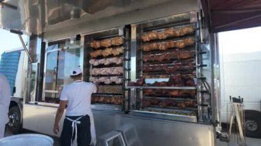 Torrevieja 'da bir markette kızarmış tavuk ve ızgara et satan bir satıcı arkasında sıra sıra kızarmış yiyecekler ve fiyatlar sergileniyor..