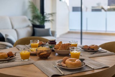 Simitler, kruvasanlar, yumurtalar, portakal suyu ve reçelli düzgün bir kahvaltı masası..