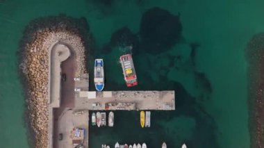 Benidorm marinasının rıhtım boyunca yanaşan teknelerinin yukarıdan aşağı görüntüsü. Buna Vision Submarina turist botu da dahil. Sahne, Akdeniz sularını ve etrafındaki kayalık kıyı şeridini yakalıyor..