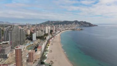 Benidorm 'un gökdelenlerle kaplı geniş plajlı havadan çekilmiş görüntüleri şehrin kıyı güzelliğini ve Akdeniz boyunca uzanan kentsel ufuk çizgisini gözler önüne seriyor..
