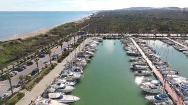 Guardamar del Segura marinasının havadan çekilmiş görüntüleri rıhtımdaki tekneleri, sakin suları ve temiz gökyüzünün altındaki palmiye ağaçlarını gösteriyor..