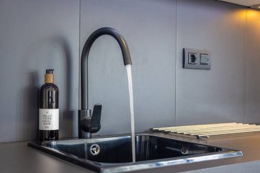 Modern mutfağın içinde siyah bir lavabo ve musluk, su akışı ve 