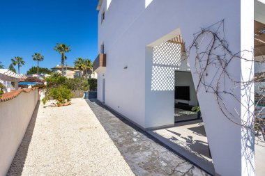 Temiz çizgileri ve bahçe elementleri olan beyaz minimalist bir villanın dış yolu..