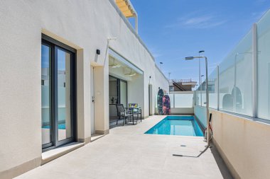 Dar özel havuzlu modern güneş terası, açık hava duşu ve sörf tahtaları olan dinlenme yeri..