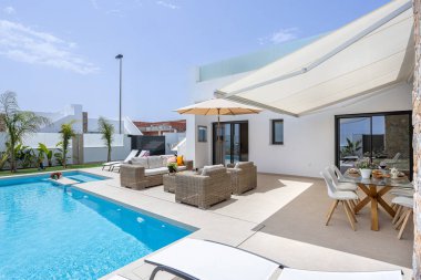 Havuzu, şezlongları, şemsiyesi ve oturma odası olan güneşli, modern bir avlu. Rahatlamak ve eğlenmek için mükemmel..