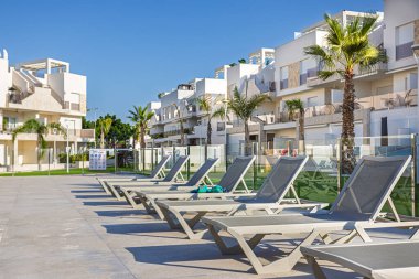 Çoklu güneş panelleri palmiye manzaralı çağdaş bir apartman kompleksinin havuz alanında..