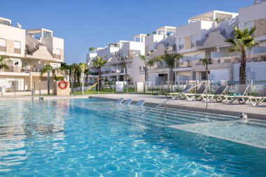 Giriş merdivenleri olan köpüklü yüzme havuzu, sualtı güneşlikleri ve bölgeyi çevreleyen modern cam çitler..