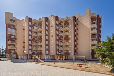 Konut yüksek binaları ve geniş fayanslı geçitlerle çevrili bir oyun parkına sahip şehir avlusu.