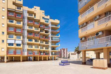 Döşeme döşemeleri, klimalı üniteleri ve canlı İspanyol bankları olan apartmanlar arasında geniş bir alan..