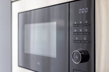 Çağdaş bir mutfak tasarımına entegre edilmiş, dijital ekran ve modern kontrol paneli olan şık bir mikrodalganın ayrıntılı görüntüsü.