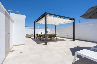 Geniş çatı terası, gölgeli yemek alanı, açık gökyüzü manzarası ve açık hava duşu..