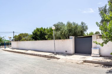 Sokak manzarası girişi ve yüksek duvarları gösteriyor..