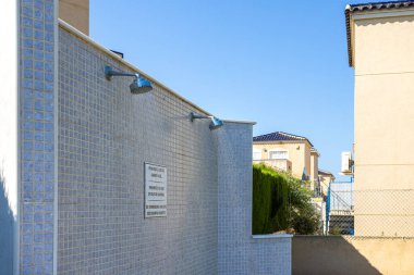 Duş başlıklarının yakın çekimleri ortak bir açık havuz tesisindeki fayanslı duvara monte edildi..