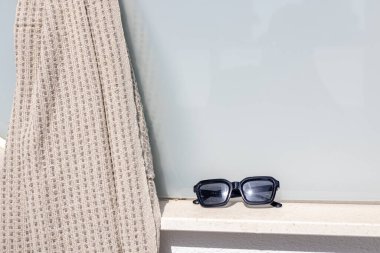 Güneş gözlüğü ve havlu güneşli teras çıkıntısına yerleştirilmiş..