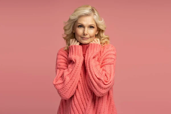 스웨터를 아름다운 여성의 배경에 고립되어 중년의 스튜디오에서 사진을 포즈를 취하고 — 스톡 사진