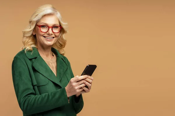 Gözlüklü Gülümseyen Olgun Bir Kadının Portresi Elinde Bej Arka Planda — Stok fotoğraf