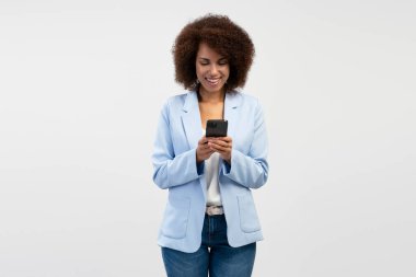 Gülümseyen Afro-Amerikan iş kadını arka planda izole edilmiş cep telefonu mesajı okuyor. Teknoloji konsepti  