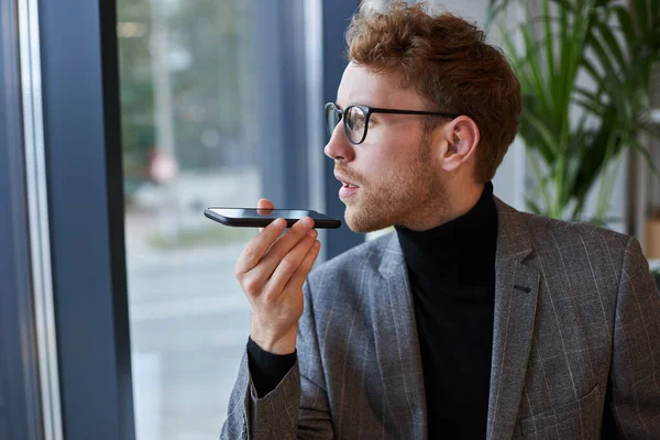 Young Pensive Man Wearing Eyeglasses Holding Mobile Phone Recording Voice —  Fotos de Stock