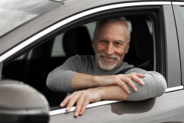 Confident portrait handsome senior man, new car owner, sitting on driver's seat with fasten belt, smiling a cheerful toothy smile looking at camera. Buying automobile. Success Driving People concept