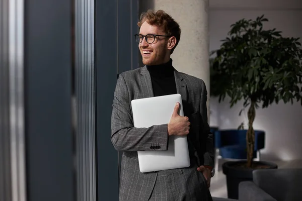 Senyum Menarik Pria Mengenakan Kacamata Memegang Laptop Melihat Jendela — Stok Foto