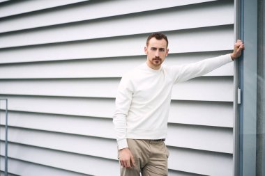 Sıradan kıyafetler giyen çekici bir adamın portresi. Sokakta kameraya bakıyor, fotokopi çekiyor. Açık havada çekilen resimler için başarılı bir model.