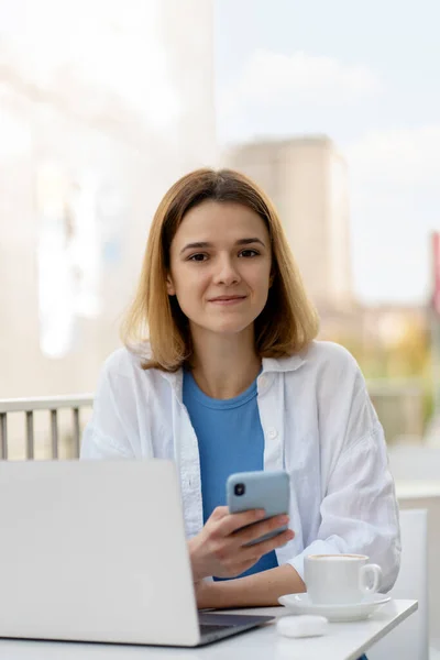 Young Woman Holding Mobile Phone Using Laptop Computer Looking Camera — Stock Photo, Image