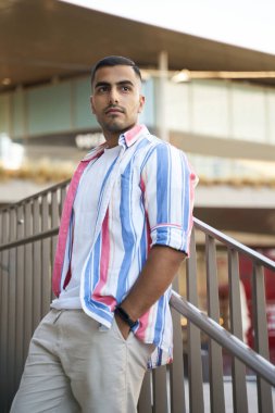 Yakışıklı düşünceli İranlı erkek model dışarıda duran resimler için poz veriyor. Şık bir adam sokakta dinleniyor ve başka tarafa bakıyor.