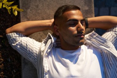  Orta Paskalya 'lı adam sokakta gözleri kapalı yatıyor ve güneşin altında dinleniyor. Öğrenci ara veriyor, dijital detoks konsepti                               