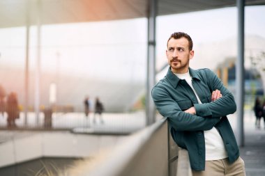Confident serious red haired man wearing stylish casual clothing looking away and standing arms crossed on the street, copy space. Positive lifestyle concept