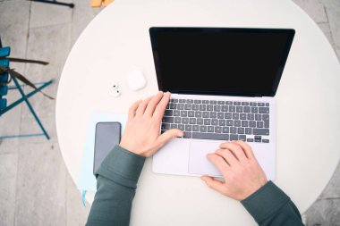 Top view of freelancer hands using laptop computer working online, looking at black screen sitting at workplace, selective focus. Mockup