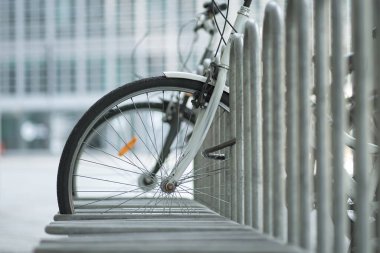Modern bicycles are parked in the metal bike parking. Bicycles stand in special place. Bicycle rental service in the street concept