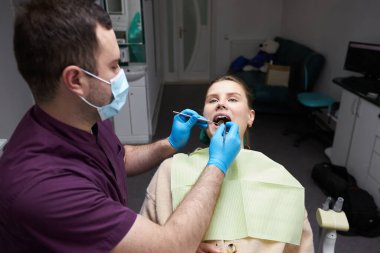 Caucasian young pregnant woman on dentist's chair, with her mouth open, at check-up in dental clinic. Conscious patient visiting oral hygienist. Dentistry. Stomatology. Oral care and hygiene