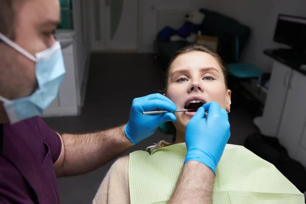 选用不锈钢工具和牙镜检查卫生工作者的双手 检查牙科诊所张嘴躺在牙医椅子上的女病人的口腔 牙科学概念 — 图库照片