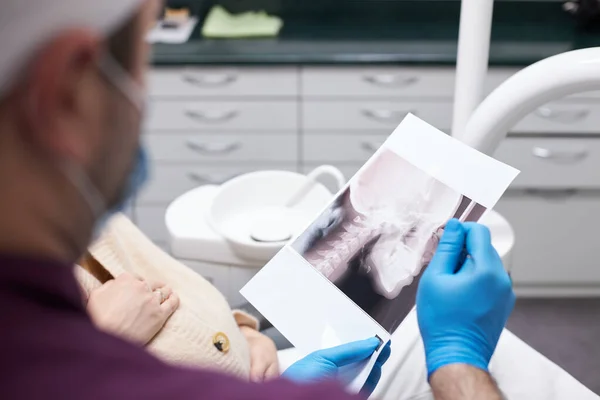 Selective focus on dental x-ray panoramic radiography in dentist doctor hands, explaining to his patient on all the dental treatment that needs to do in dentistry. Dental care. Medicine and healthcare