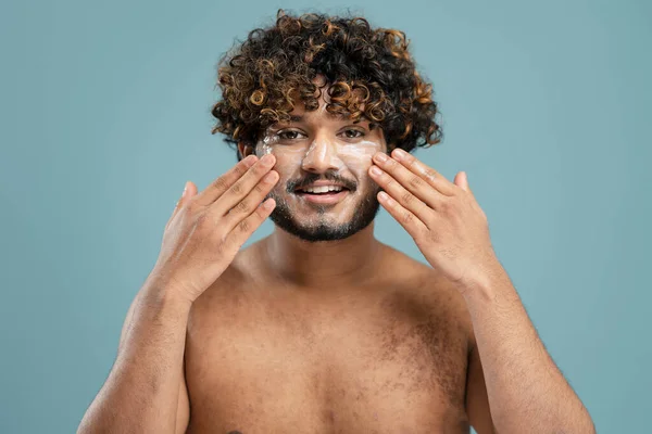 Close Portrait Young Curly Haired Bearded Asian Man Spreading Moisturizer — Stok fotoğraf