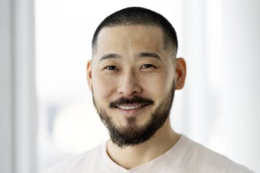 Portrait of a handsome, smiling man with a beard on a white background. Emotional hipster looking at camera. Positive lifestyle concept