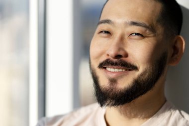 Closeup portrait of an attractive smiling Asian man. Cheerful guy looking at camera, copy space